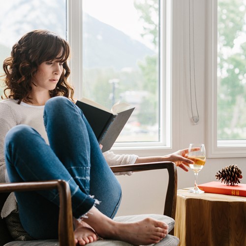 Elk & Avenue Hotel guest drinking wine and reading a book, Banff, Canada