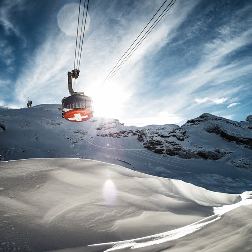 rotating cable car over snow slopes and blue skies in engelberg