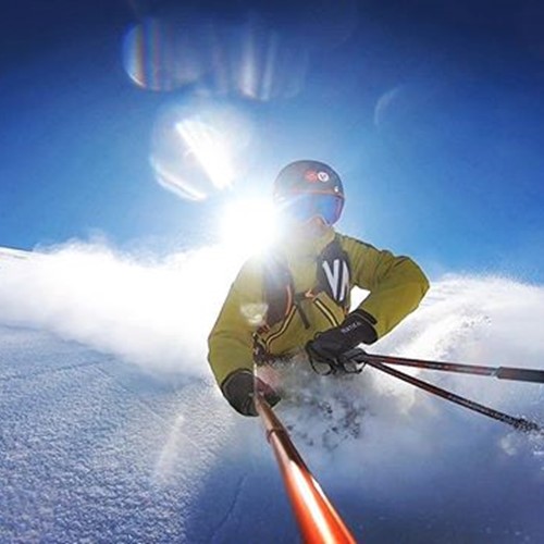 man skiing through powder selfie stick