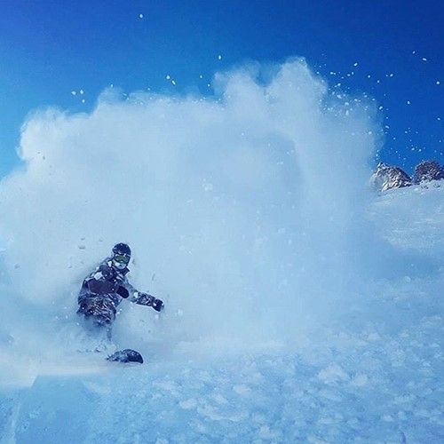 snowboarder kicking up powder cloud on slopes