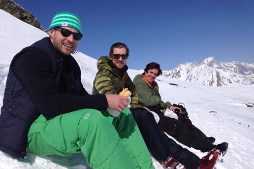 three men enjoy a sandwich on the slopes